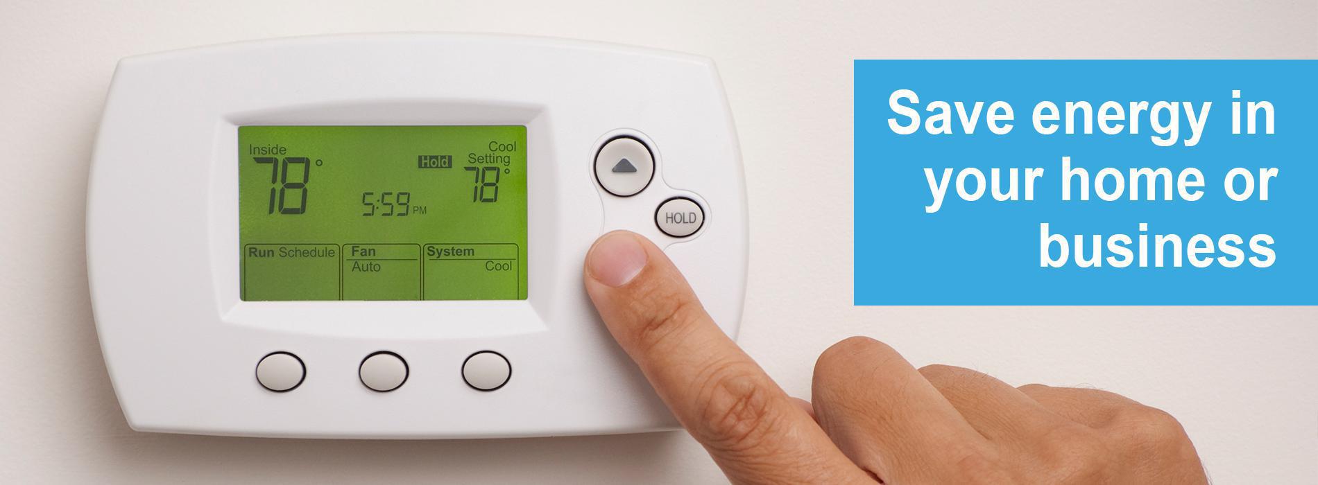 Finger turning down the thermostat with words saying "Save energy in your home or business"
